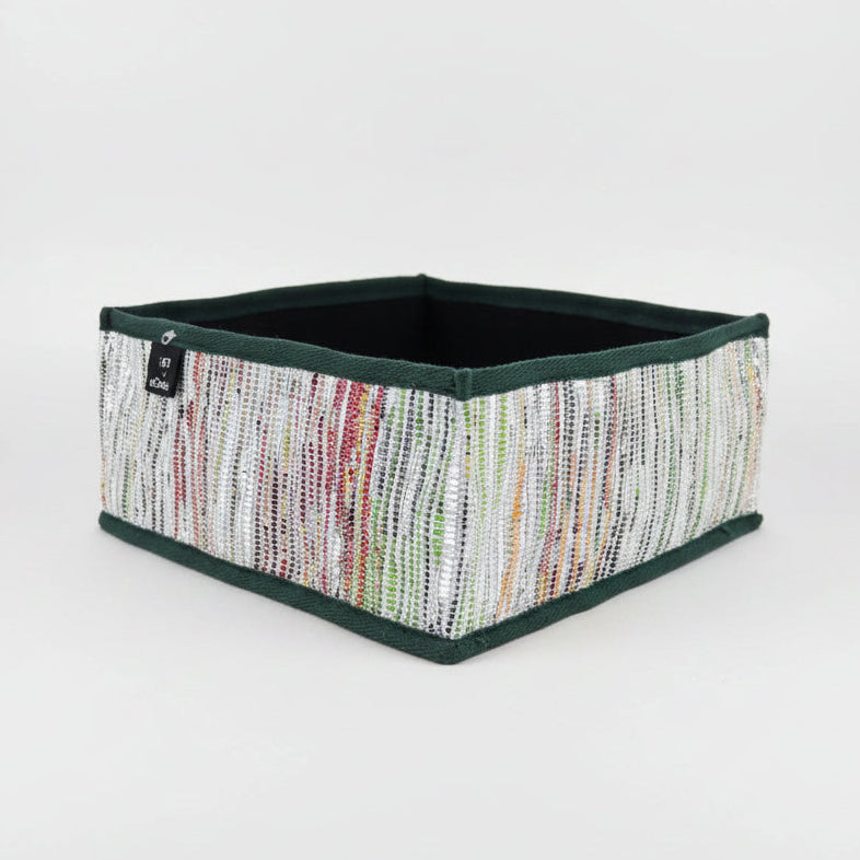 Collapsible storage box in multicolored weave with a dark green trim.