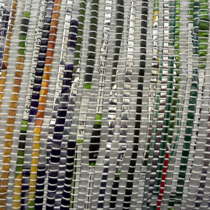 Close-up of handwoven collapsible storage basket small in a multicolored weave and dark green trim.