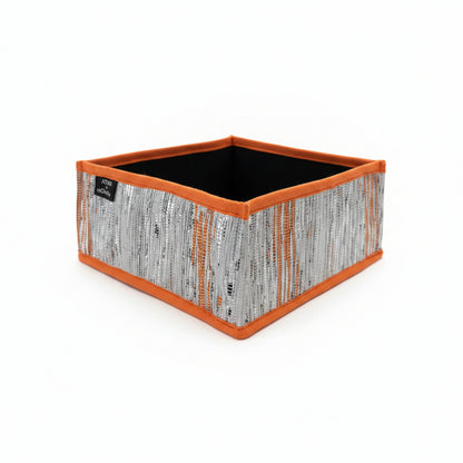 Collapsible storage box small with an orange trim with silver and orange weave.