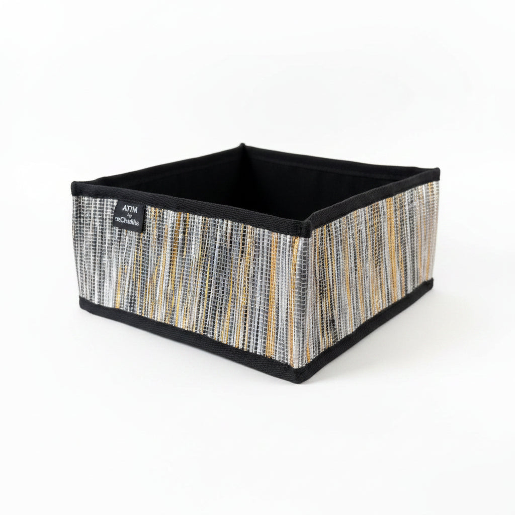 Upcycled handwoven collapsible storage box in gold and black weave and black trim.