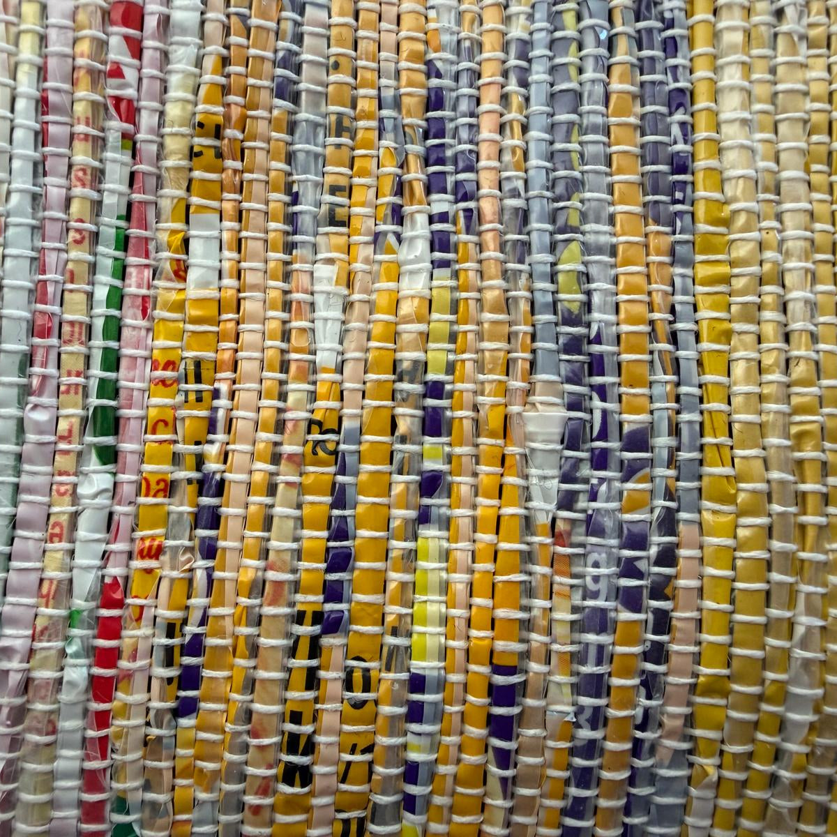 Close-up of an upcycled handwoven collapsible storage box in a multicolored weave with a beige trim.