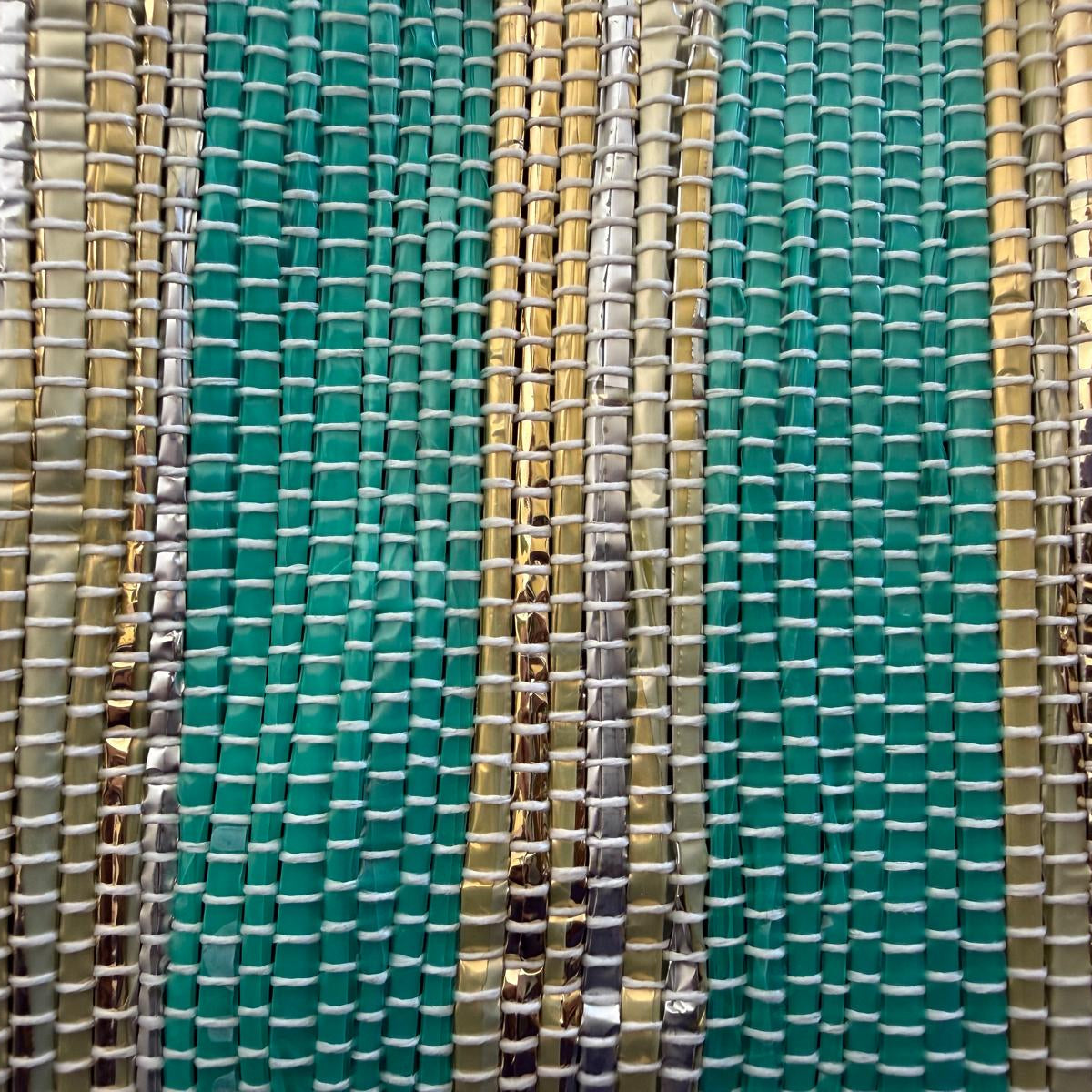 Close-up of an upcycled handwoven collapsible storage basket weave with green and gold stripes and beige trim.
