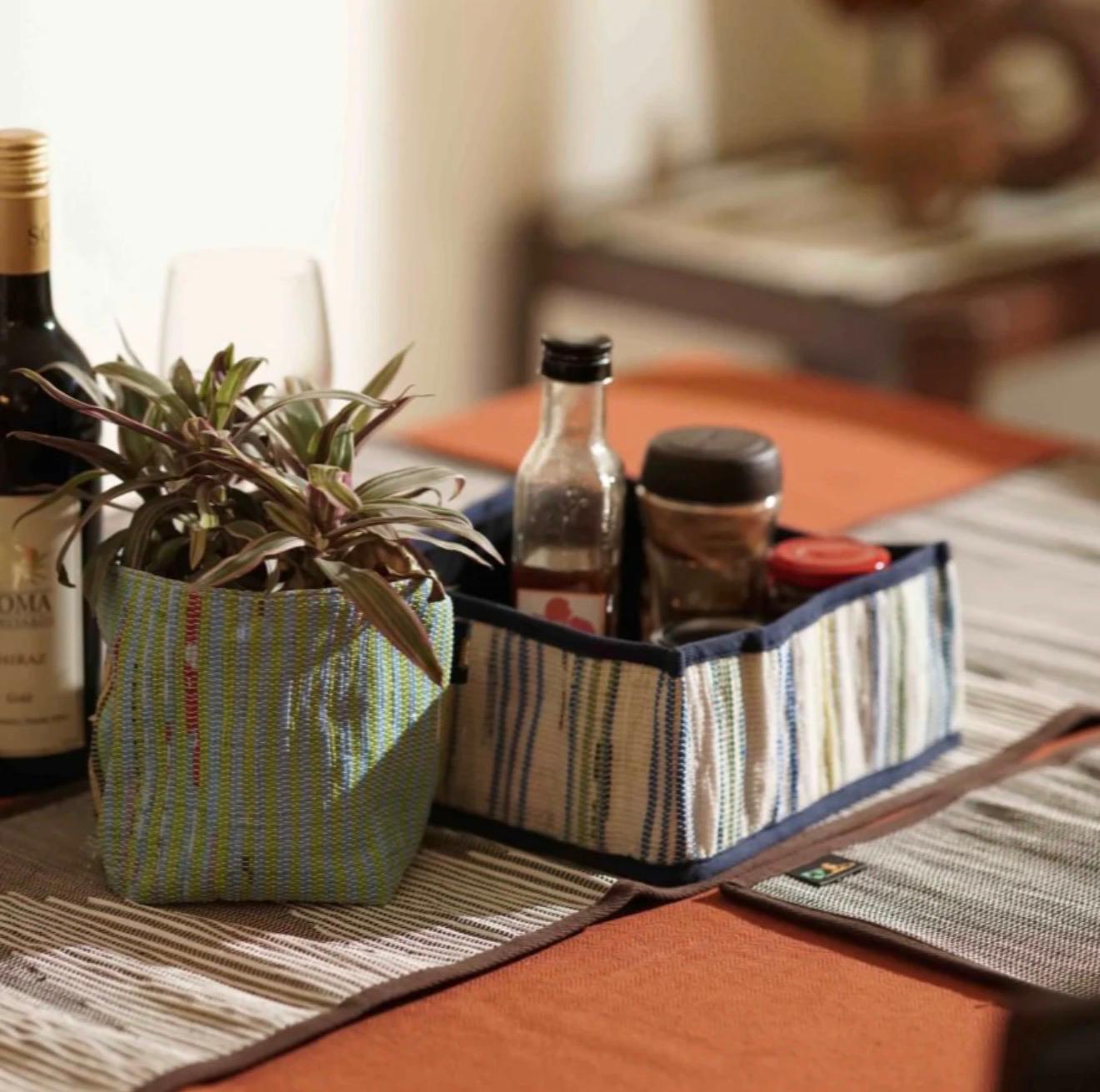 Collapsible storage basket small used on a table setting to hold condiment bottles.