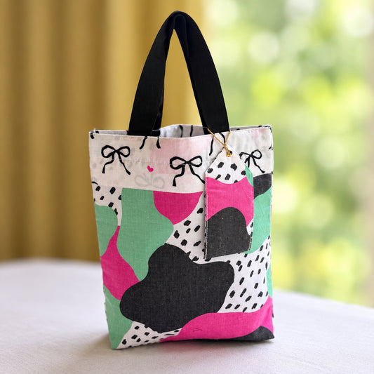 Reusable Fabric Gift Bag with matching gift tag holder in a abstract print and a bow print top border with black handles.