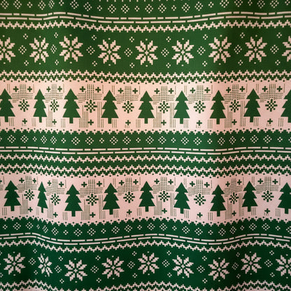Patterned fabric with Christmas trees, snowflakes, and geometric shapes on a green and white background.