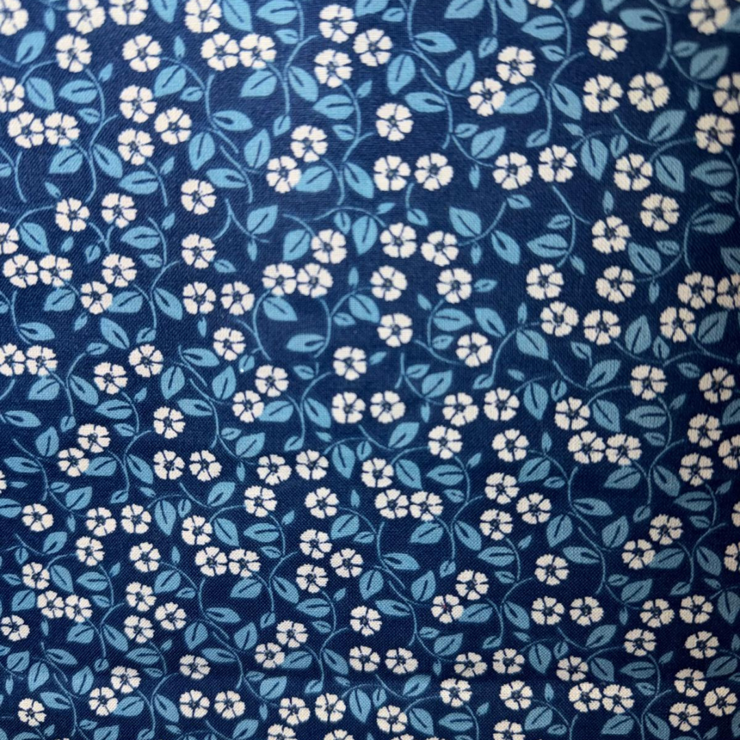 Navy blue floral pattern with small white flowers and blue leaves on a dark blue background
