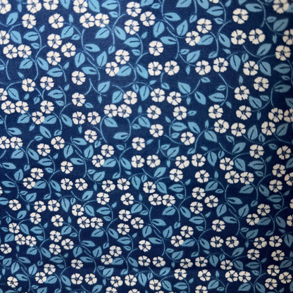 Navy blue floral pattern with small white flowers and blue leaves on a dark blue background