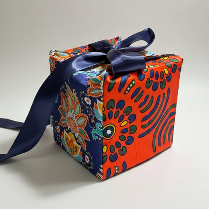 Eco-friendly gift box in a bold African print, in orange & blue with a ribbon closure.