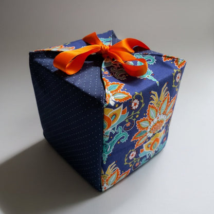Reusable gift wrap in a bold African print, in orange & blue dots with a ribbon closure.