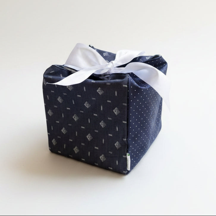 Navy blue dotted fabric gift box with a white ribbon closure in 7X7X7 square size.