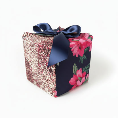 Colorful reusable gift box in pink & blue speckled & floral cotton fabric, with a ribbon closure.