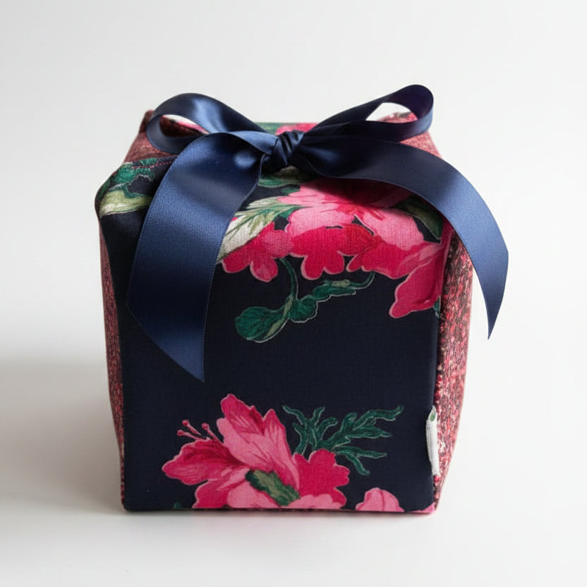 Colorful reusable gift box in pink & blue speckled & floral cotton fabric, with a ribbon closure.