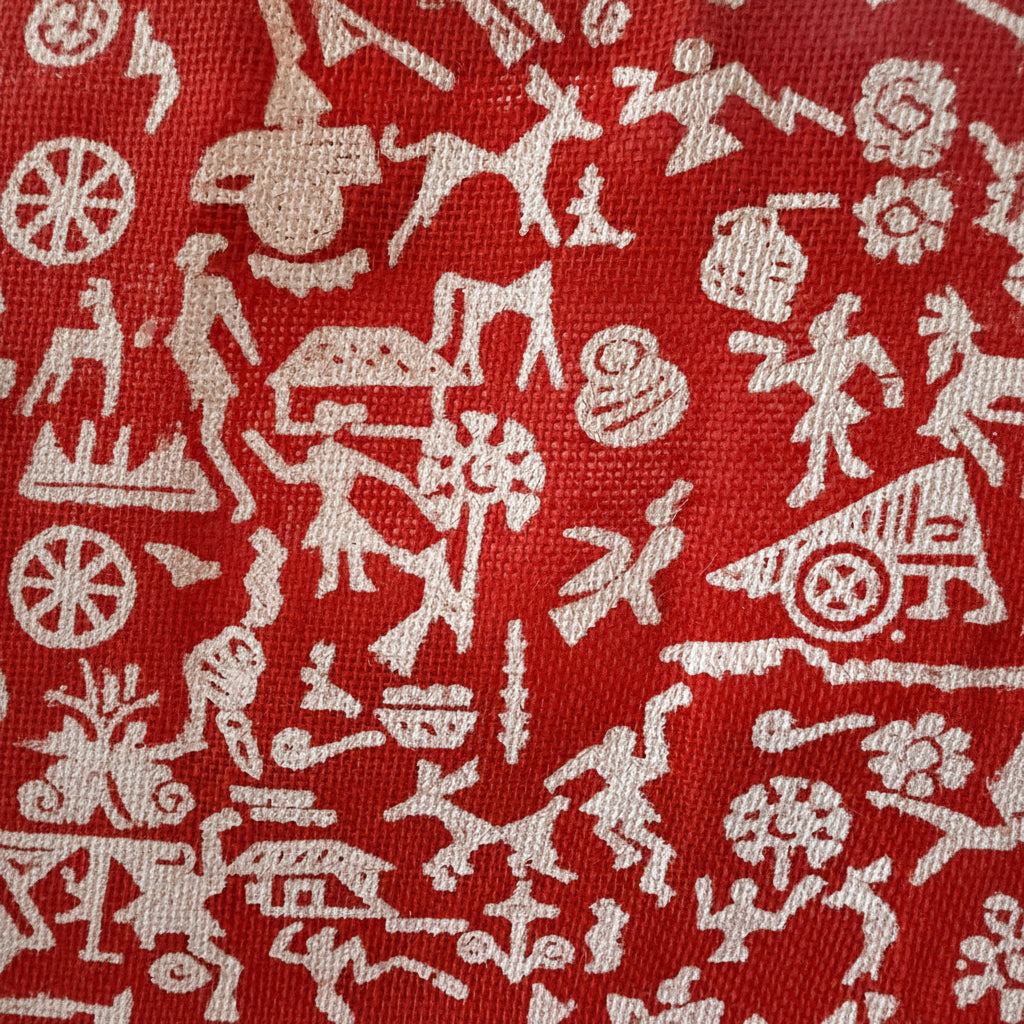 Red fabric with white abstract patterns resembling people and animals.