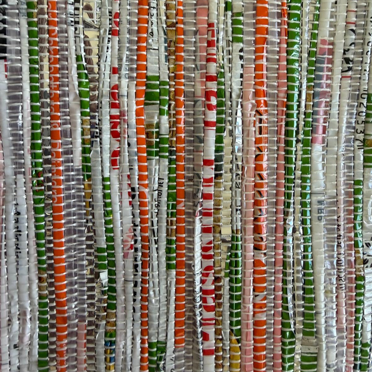 Close-up of upcycled handwoven Messenger Bag in orange and green weave with a dark green strap.