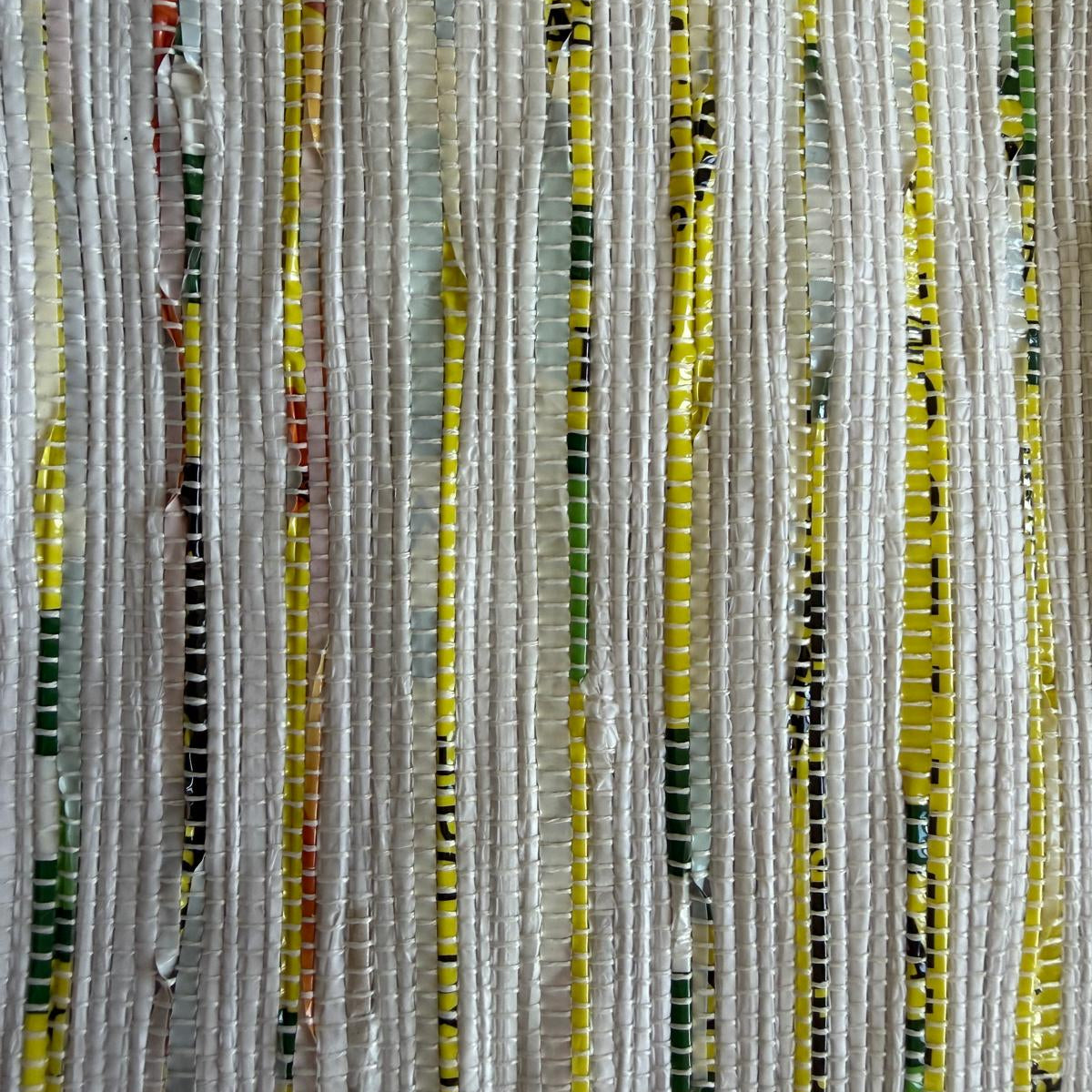 Close-up of upcycled handwoven Messenger Bag in multicolored weave with a dark green strap.