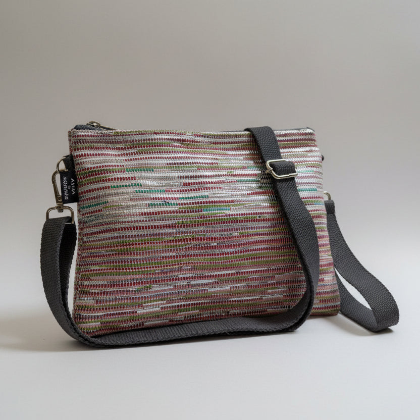 Upcycled handwoven Sling-It Bag in multicolored pink weave with a grey strap.