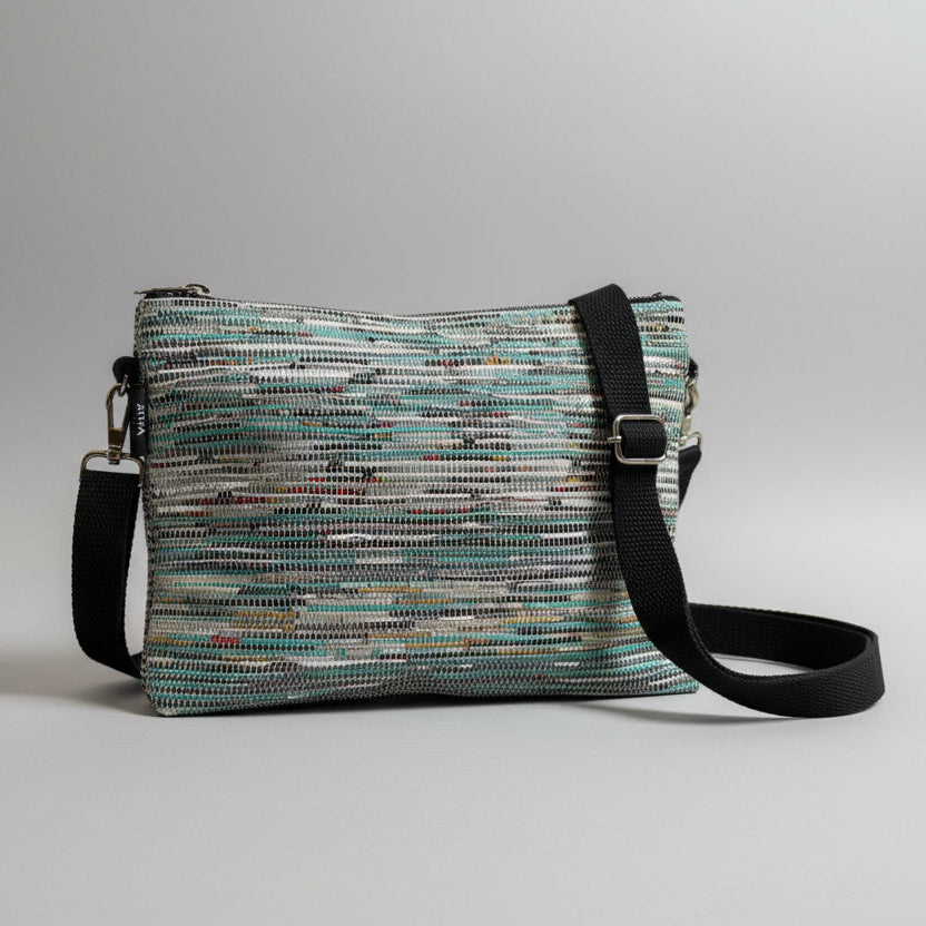 Upcycled handwoven Sling-It Bag in teal colored weave with a black strap.