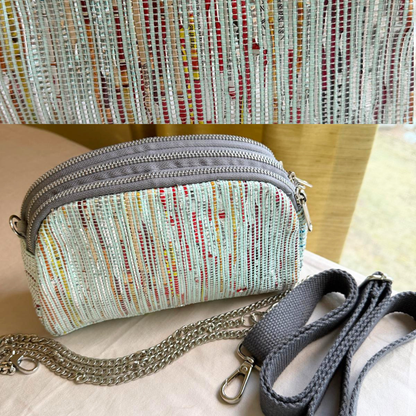 Taco Sling bag in multi-colored light blue weave with a chain, plus grey strap.